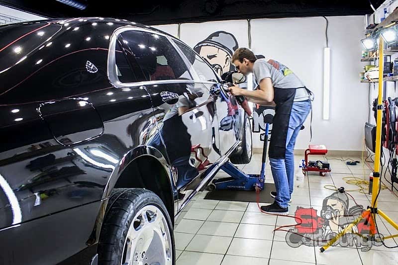 Мастер обрабатывает переднюю часть кузова 